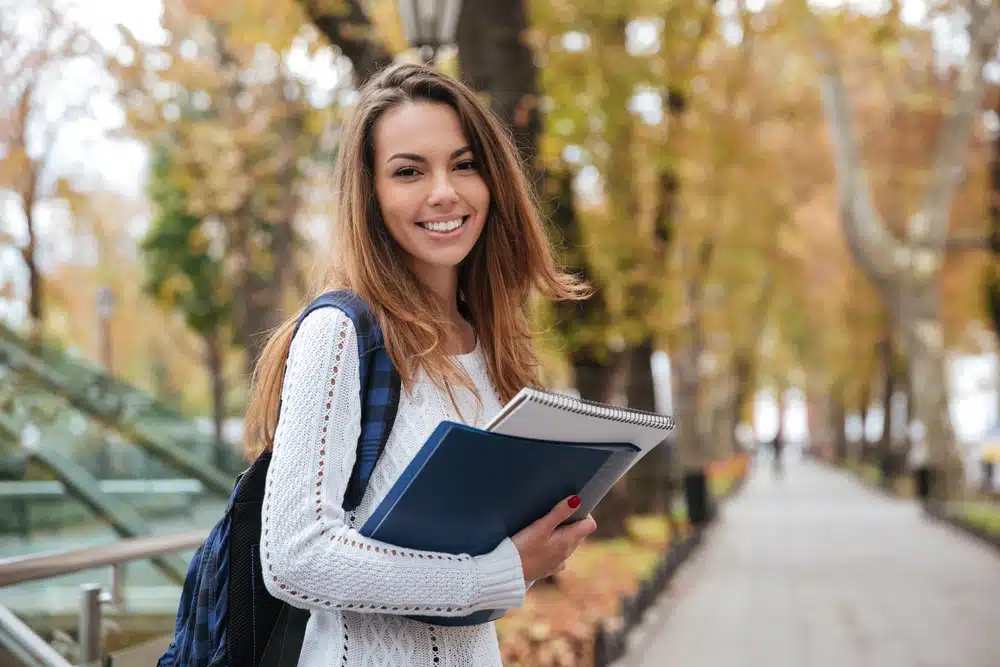 Young woman holding her books on a school campus.