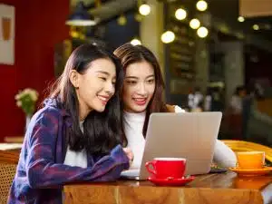 Two students talking in front of a laptop.