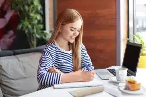 Young woman writing in a desk.