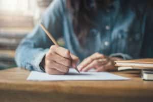 Writing in a desk using a pencil.