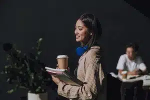 Female student holding her things while standing.