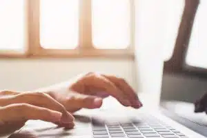 Typing in a desk using a laptop.