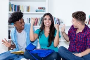 Three students talking while sitting on the library.