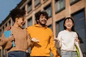 Three students walking in front of a school building.