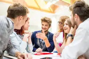 Group of students looking at each other while talking in a table.