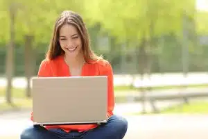 Young woman looking happy while using a laptop.