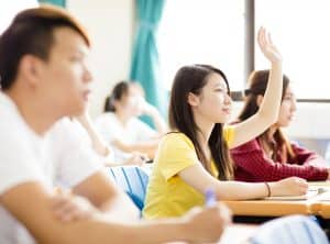 Female student raising her hand in a class discussion.