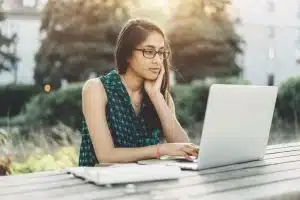 Young woman using a laptop in a bench.