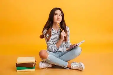 Young woman looking like she is thinking while sitting on a yellow floor.