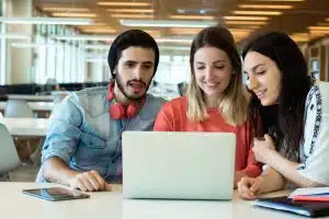 University students talking in front of a laptop.