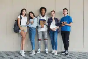 a group student standing against a wall and looking at the camera