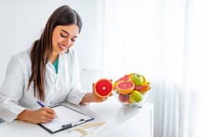 Female Nutritionist writing in a table with fruits.