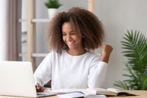 Young woman looking at her laptop and looking happy.