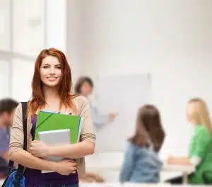 Female student holding her books while smiling for the camera.