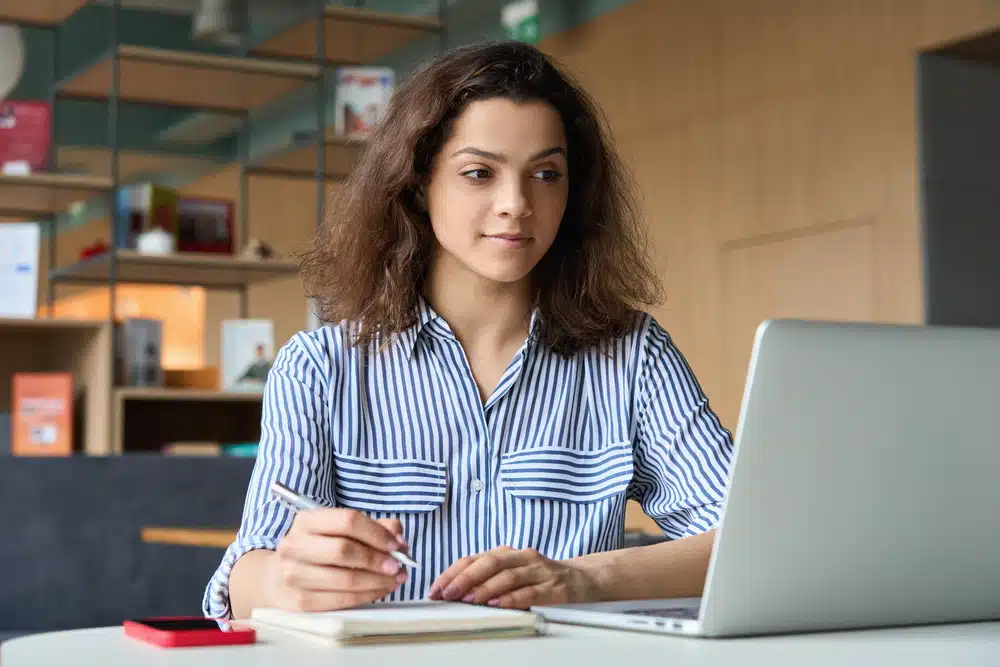 Young woman attending an online class in a room.