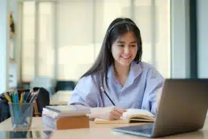 Female student using a laptop while studying on her desk.