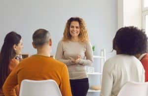 Young woman talking to a group of people.