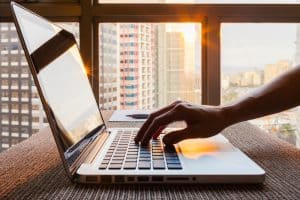 An open laptop placed on top of a table near a window of a computer science student,