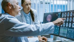 two neuroscientists analyzing a brain scan projected through the computer screen