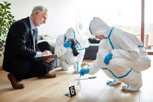 Three forensic scientist crouched in the floor while investigating a scene inside a roon