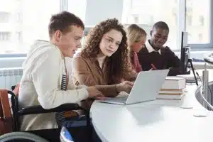 Side view of students talking in front of a laptop.