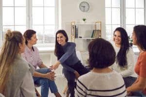 Group of students talking while huddled together in a room.