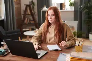 Young woman using a laptop on a desk with her notebooks.