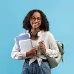 a female student smiling in front of the camera and carrying her stuff
