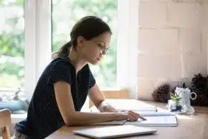 View of a woman studying in a room with a window.