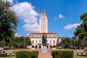Front view of a building in the University of Texas with a male statue at the very front