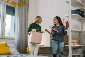 Two students packing their things in a dorm room.