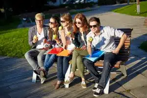 Group of students eating on a bench while eating.