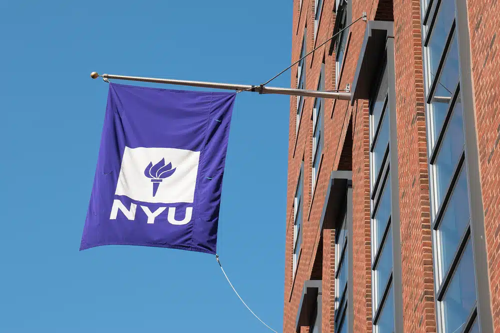 The university flag New York University propped outside of its building.