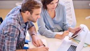 Two people talking and discussing while sitting on a table.