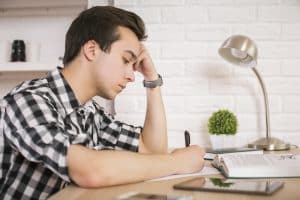 A male student writing in his desk.