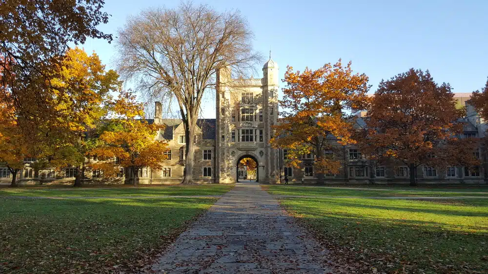 Front view of the University of Michigan with an empty yard filled with different varieties of trees