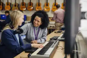 Female teacher talking to a student in a music room.