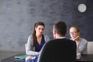 Young woman talking to a principal and a teacher in a room.