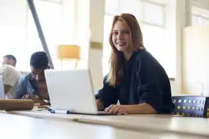 A female student seated in a room with her laptop in front of her after