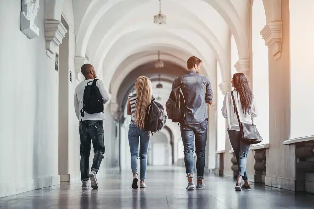 a group of college students walking side by side in a hall way