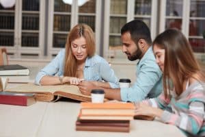 Group of students working on a table in a library.