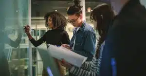 a group of student looking through their notes while one of them is writing something on the glass board