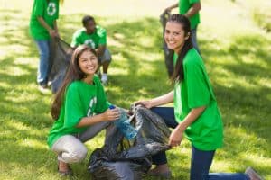 two female students holding a garbage bag while picking up garbage