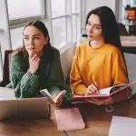 Two students talking on a table.