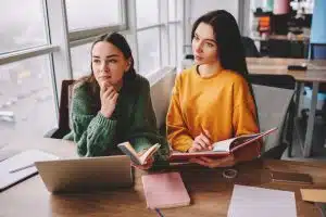 Two students talking on a table.