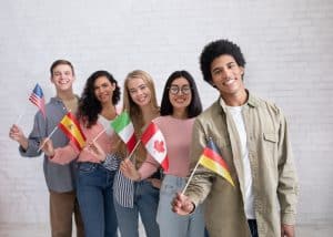View of students raising the flags of their country while smiling for a picture.
