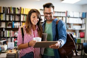 Two students staring at a tablet in a library.