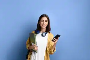 Female student holding her things while smiling at the camera.