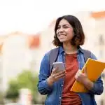 a student smiling while holding her phone