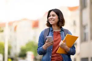 a student smiling while holding her phone